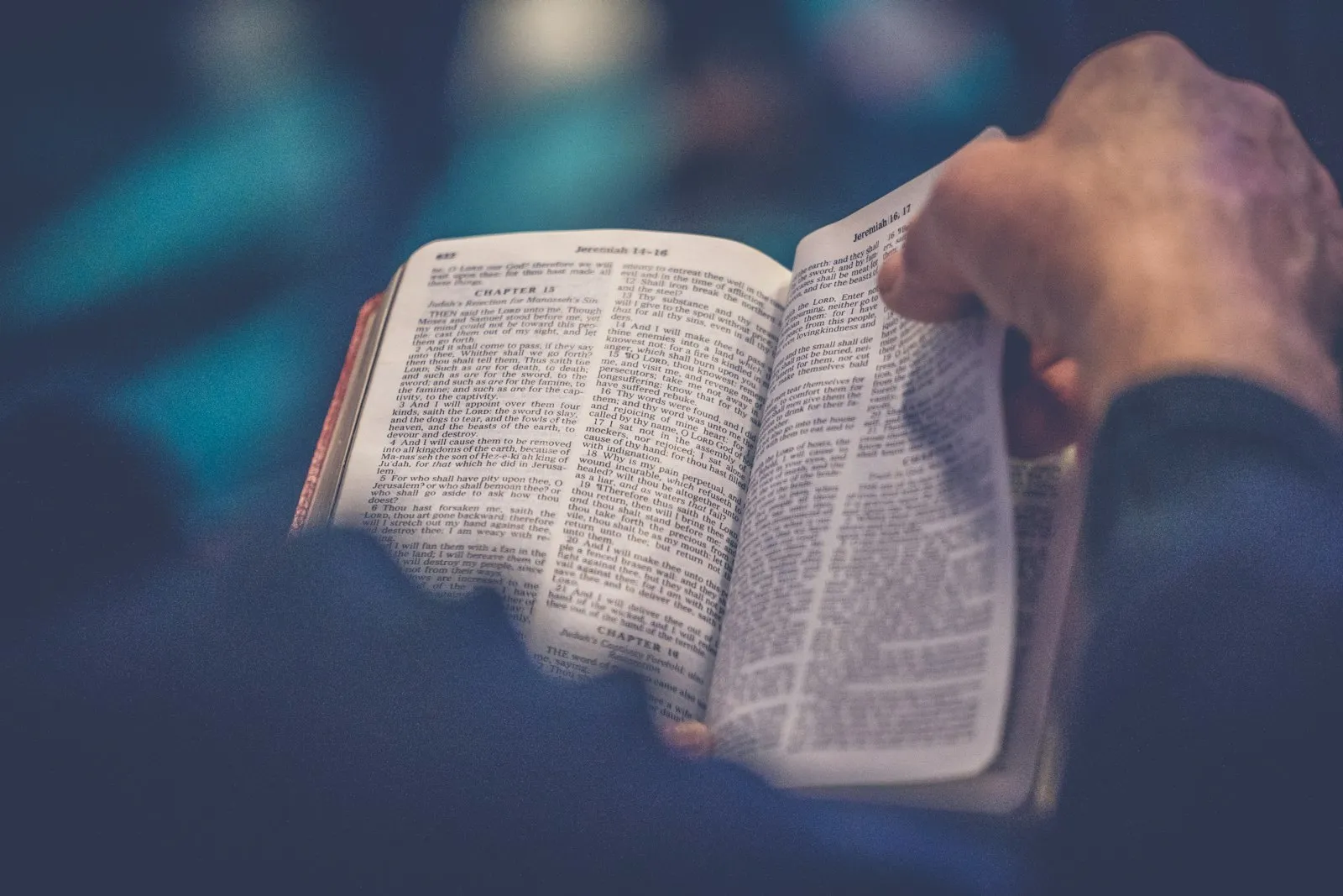Hands holding an open Bible in soft blue light